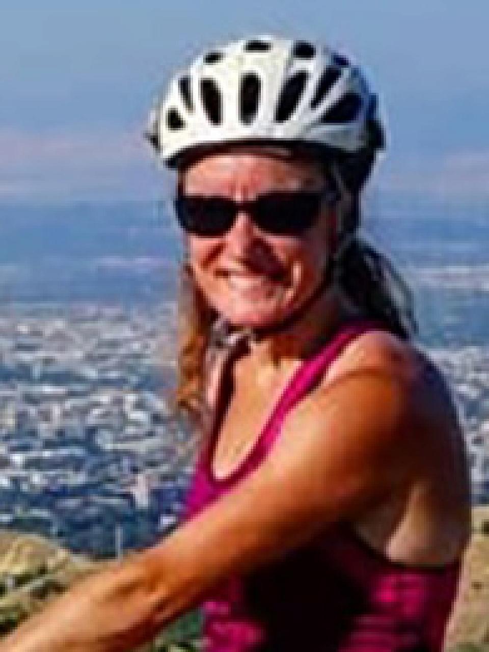 Woman with blond wavy hair, helmet and pink tank top