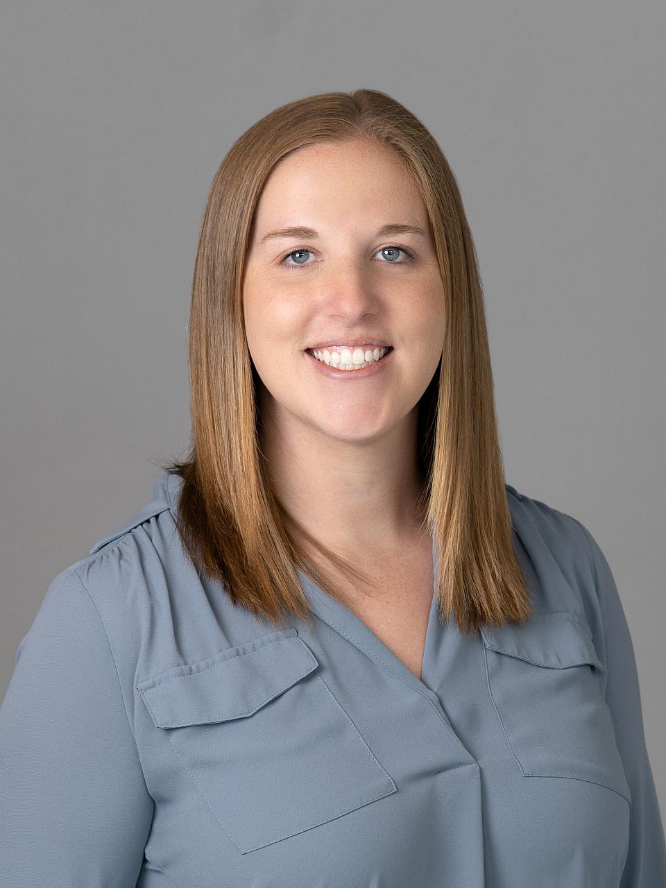 Photo of a woman, Dr. Alison Brann, with brown hair wearing a blue-gray shirt smiling at the camera.